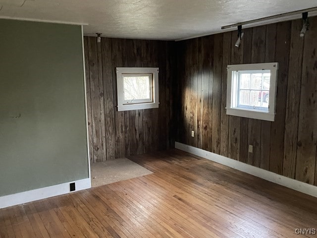 spare room featuring wood walls and light hardwood / wood-style floors