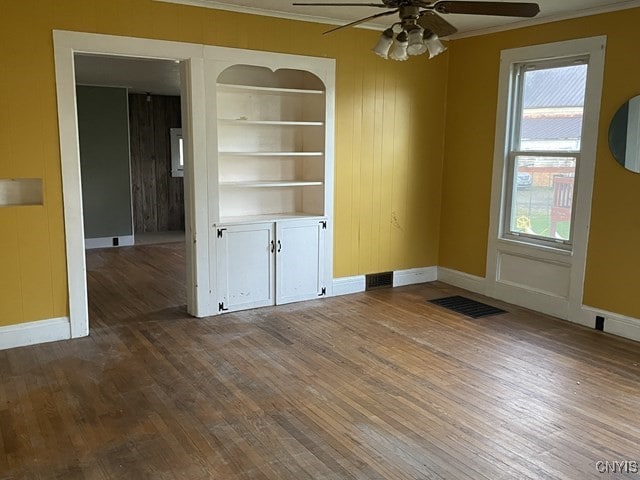 spare room featuring wood-type flooring, ceiling fan, and ornamental molding