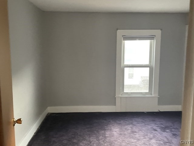 unfurnished room featuring dark carpet