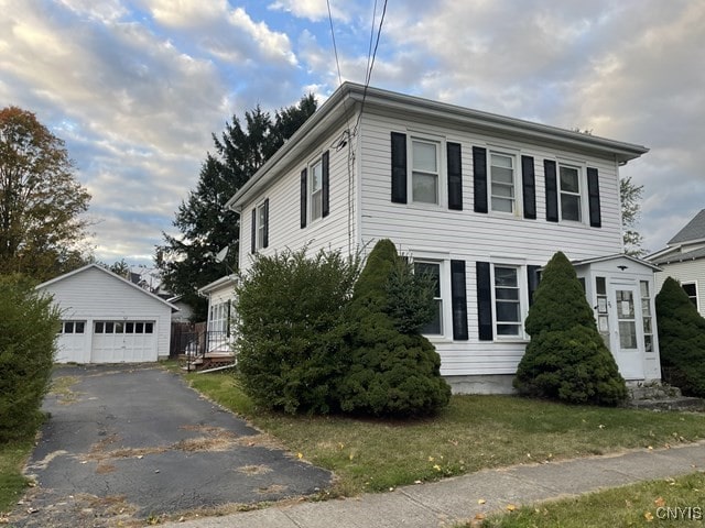 view of front of house with a front yard, a garage, and an outdoor structure