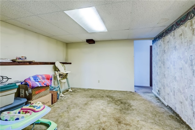 basement with a paneled ceiling and carpet floors