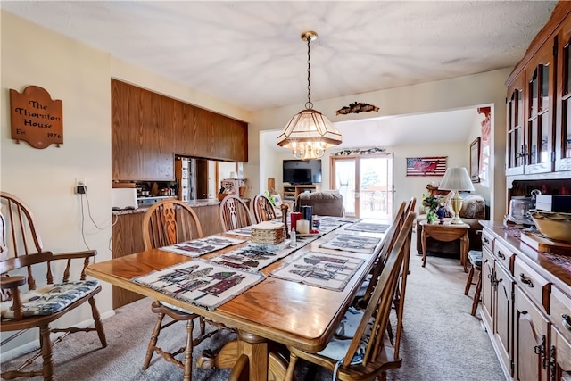 carpeted dining room featuring a chandelier