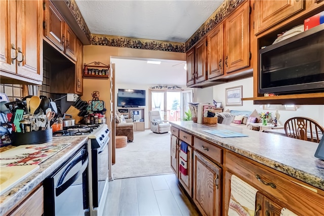 kitchen featuring light colored carpet, white appliances, and a textured ceiling