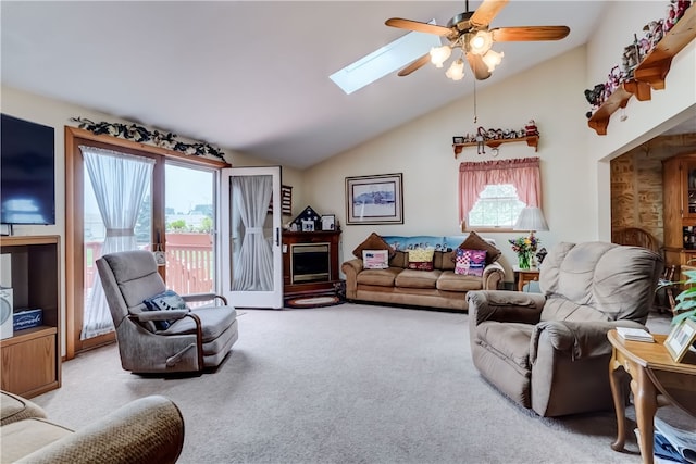 carpeted living room with lofted ceiling with skylight, plenty of natural light, and ceiling fan