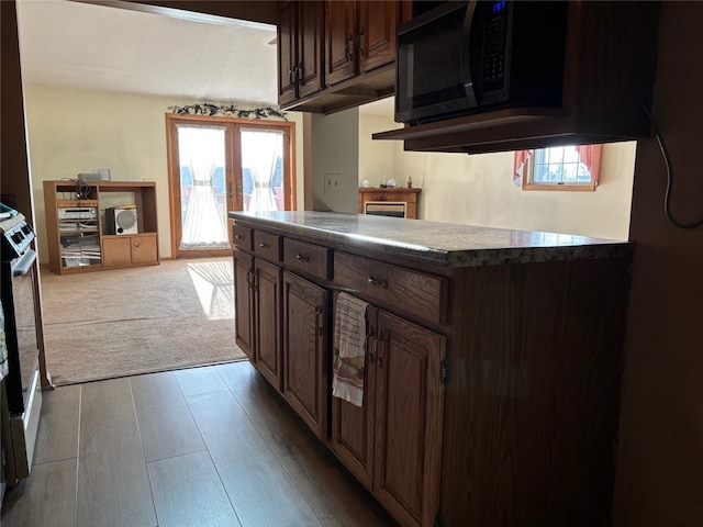 kitchen featuring dark brown cabinets, light hardwood / wood-style floors, stainless steel range oven, and french doors