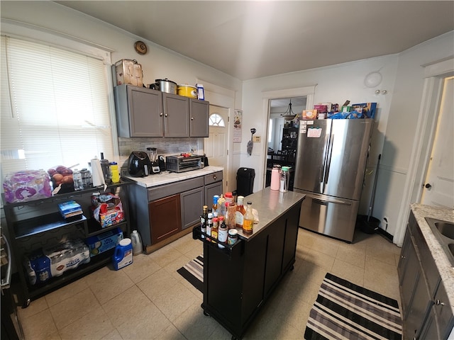 kitchen with a center island, dark brown cabinetry, backsplash, and stainless steel refrigerator