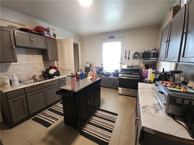 kitchen featuring appliances with stainless steel finishes, tasteful backsplash, a kitchen island with sink, and sink