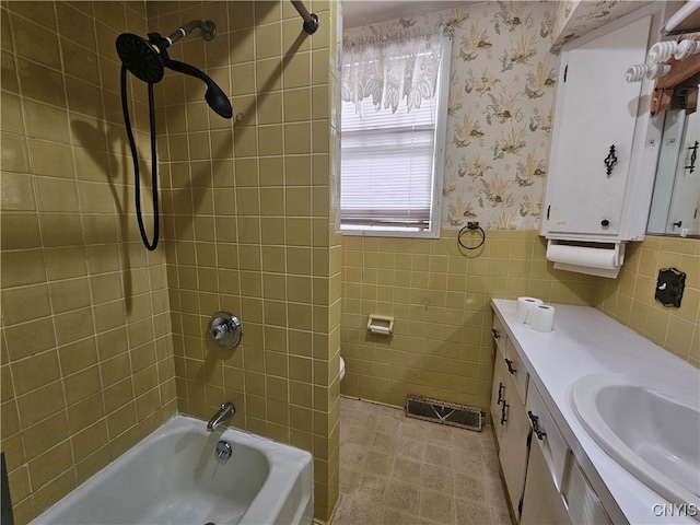 bathroom with vanity, tile walls, and tiled shower / bath