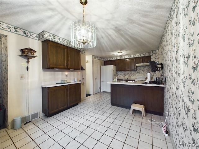 kitchen featuring a notable chandelier, dark brown cabinetry, white appliances, and kitchen peninsula