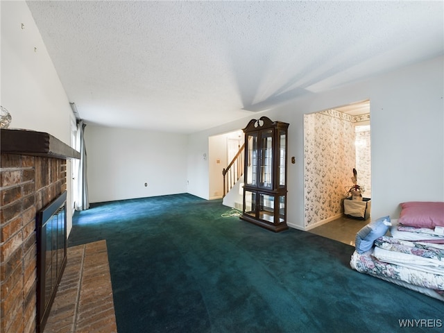 unfurnished living room with dark carpet, a textured ceiling, and a brick fireplace