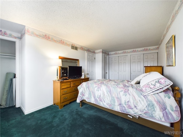 carpeted bedroom featuring a textured ceiling and multiple closets