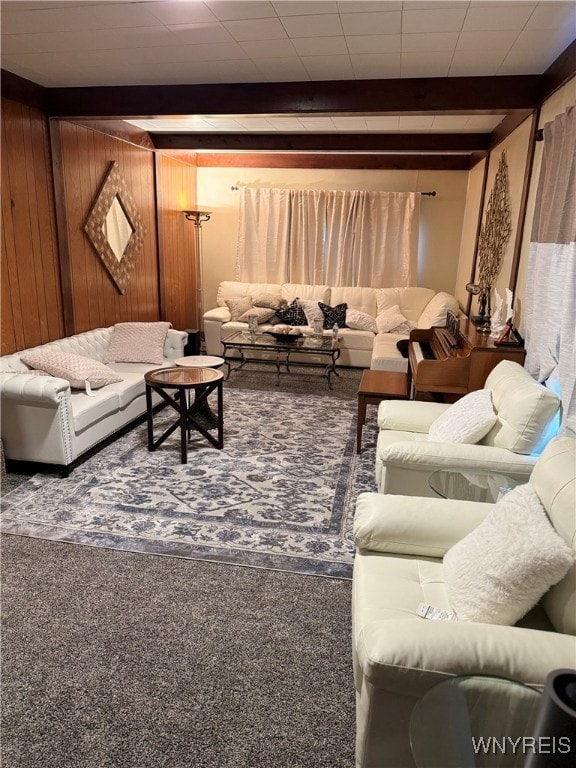 living room featuring beamed ceiling, wood walls, and carpet