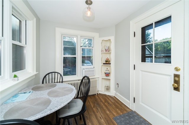 dining area featuring dark hardwood / wood-style floors, a healthy amount of sunlight, radiator heating unit, and cooling unit