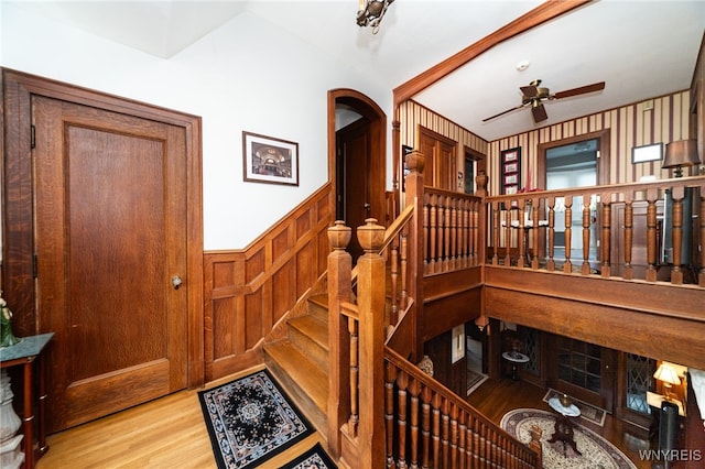 stairs with wood walls, ceiling fan, and wood-type flooring