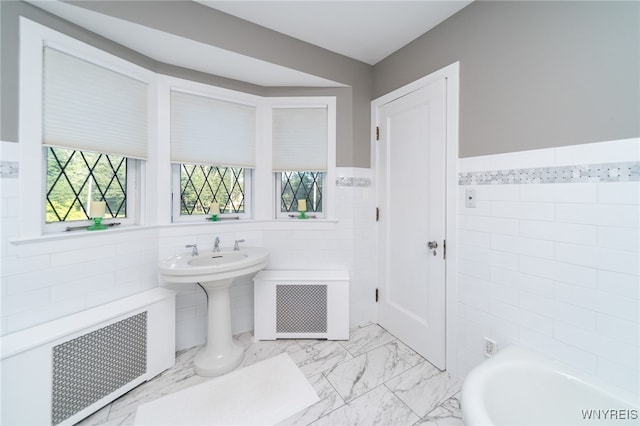 bathroom with a washtub, radiator heating unit, and tile walls