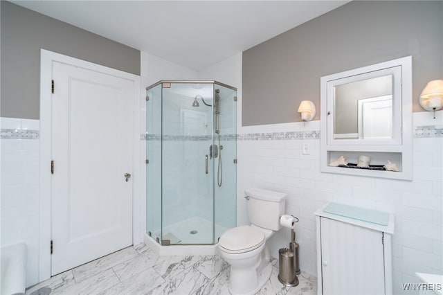 bathroom featuring a shower with door, toilet, and tile walls