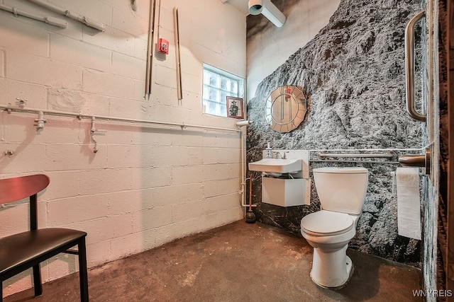 bathroom with concrete flooring, toilet, and sink