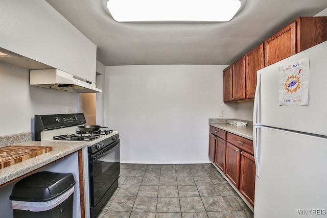 kitchen featuring black gas range, white refrigerator, and range hood