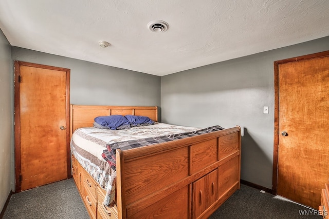 bedroom with dark carpet and a textured ceiling