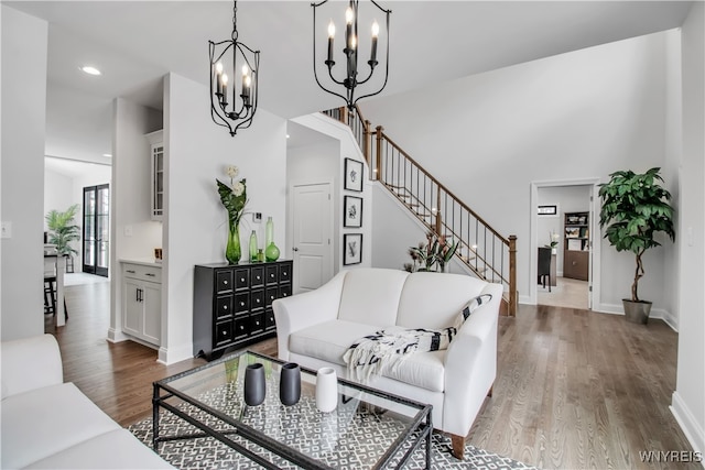 living room featuring hardwood / wood-style floors, a notable chandelier, and a towering ceiling