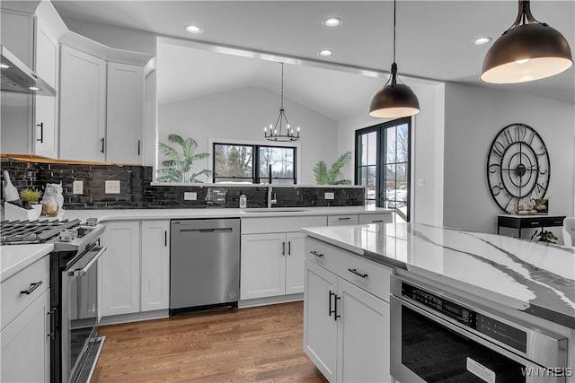 kitchen featuring tasteful backsplash, stainless steel appliances, sink, pendant lighting, and white cabinetry