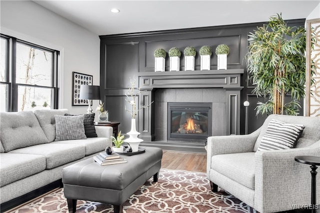 living room featuring a tiled fireplace and hardwood / wood-style floors