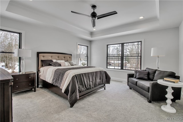 bedroom featuring light colored carpet, a raised ceiling, and multiple windows