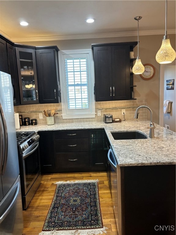 kitchen featuring light stone countertops, appliances with stainless steel finishes, decorative backsplash, sink, and light hardwood / wood-style floors