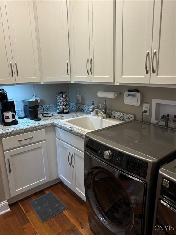 laundry area featuring washing machine and clothes dryer, cabinets, sink, and dark wood-type flooring