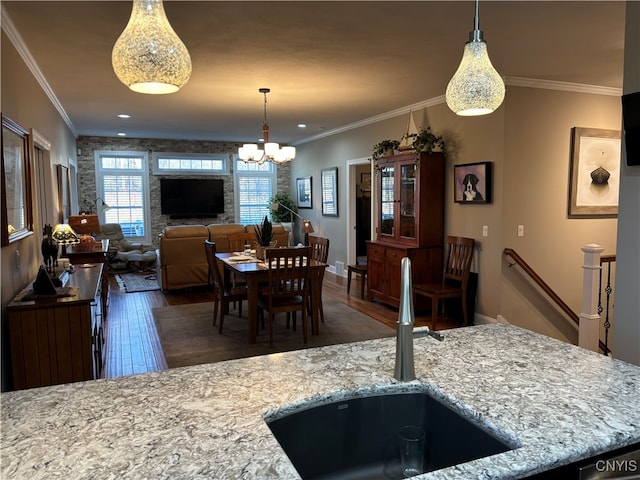 kitchen with crown molding, sink, light stone countertops, and dark wood-type flooring