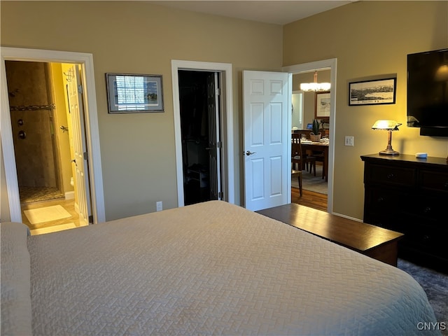 bedroom with dark wood-type flooring, ensuite bathroom, a closet, a walk in closet, and a chandelier