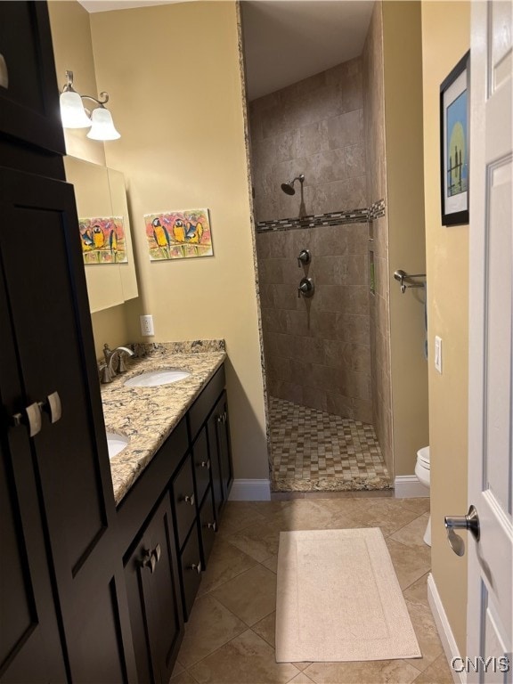 bathroom featuring tile patterned flooring, vanity, toilet, and a tile shower