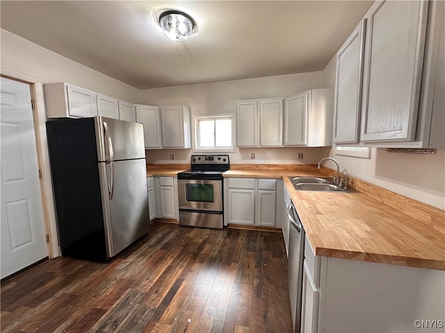 kitchen with dark wood-type flooring, sink, appliances with stainless steel finishes, butcher block countertops, and white cabinetry