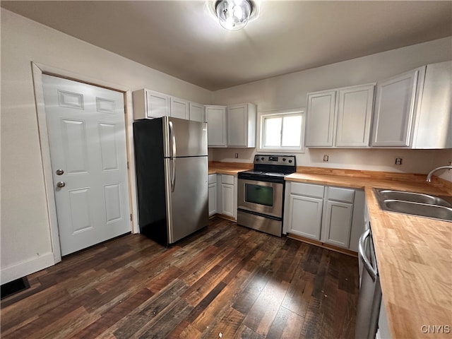 kitchen featuring dark wood-type flooring, wooden counters, white cabinets, sink, and stainless steel appliances