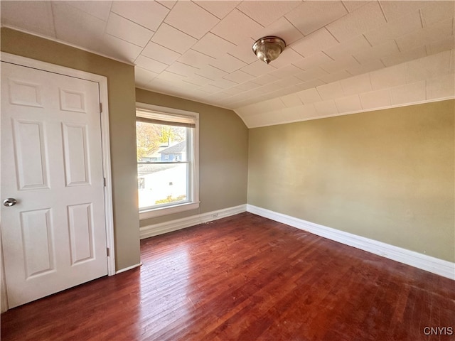 additional living space featuring dark wood-type flooring and lofted ceiling