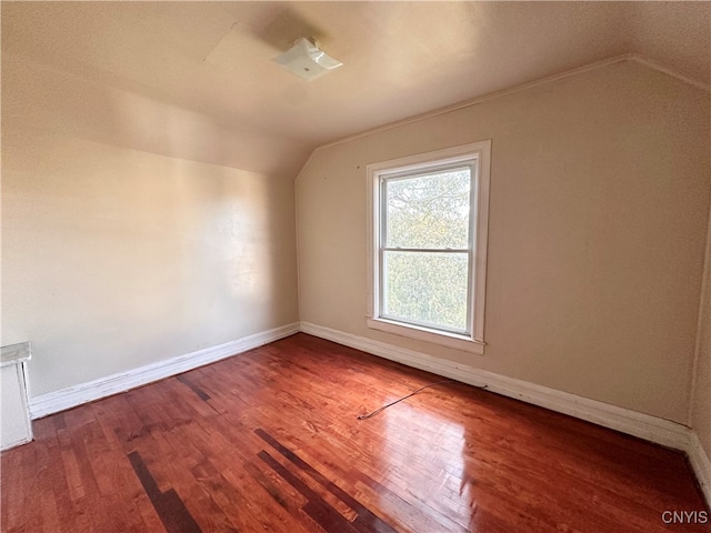 additional living space with hardwood / wood-style floors and vaulted ceiling