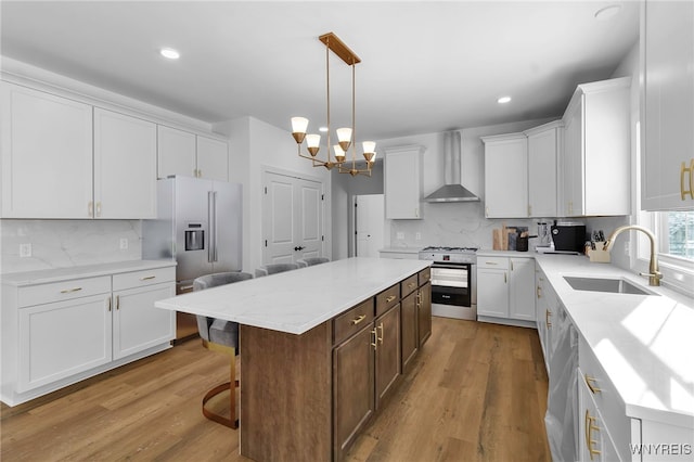 kitchen featuring white cabinetry, sink, wall chimney exhaust hood, a kitchen island, and light wood-type flooring