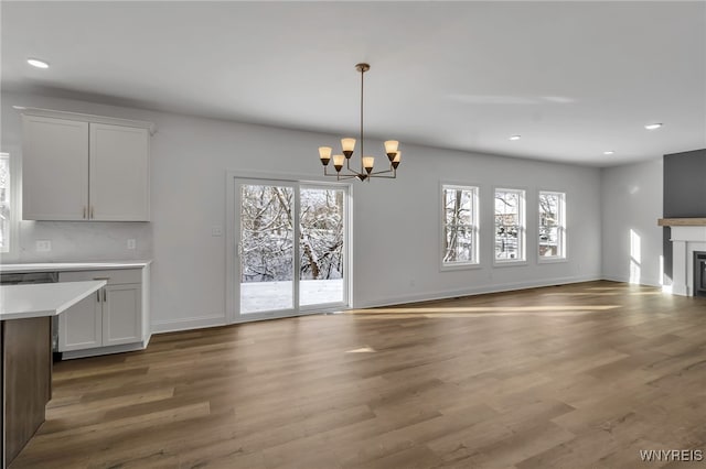 unfurnished living room featuring a chandelier, hardwood / wood-style floors, and a healthy amount of sunlight