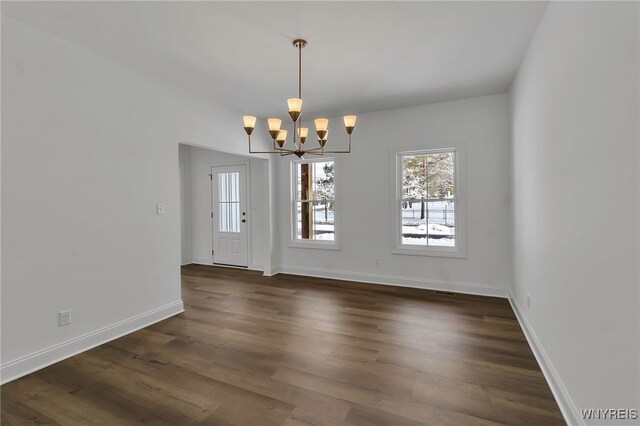 unfurnished dining area featuring dark hardwood / wood-style flooring and a notable chandelier