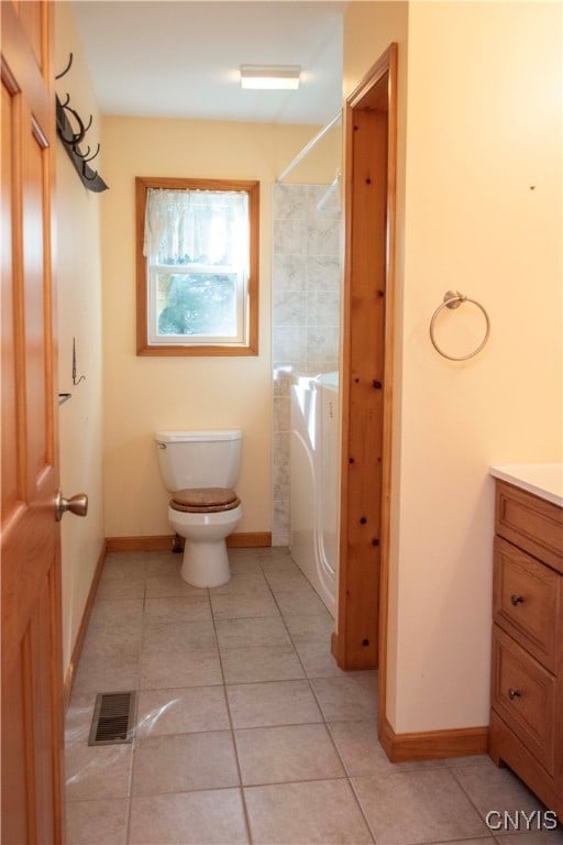 bathroom featuring tile patterned flooring, vanity, toilet, and washer / clothes dryer