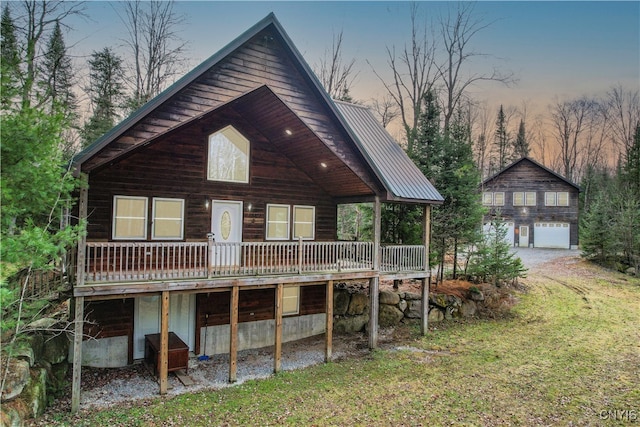 back house at dusk featuring a lawn, a deck, and a garage