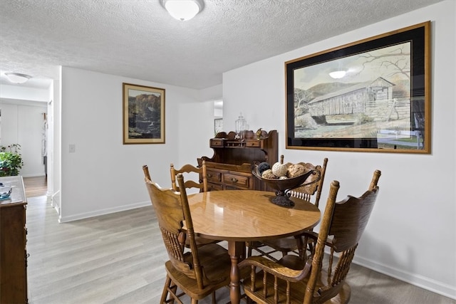 dining room with a textured ceiling and light wood-type flooring