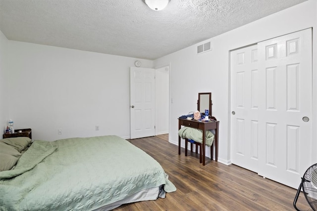 bedroom featuring dark hardwood / wood-style floors, a textured ceiling, and a closet