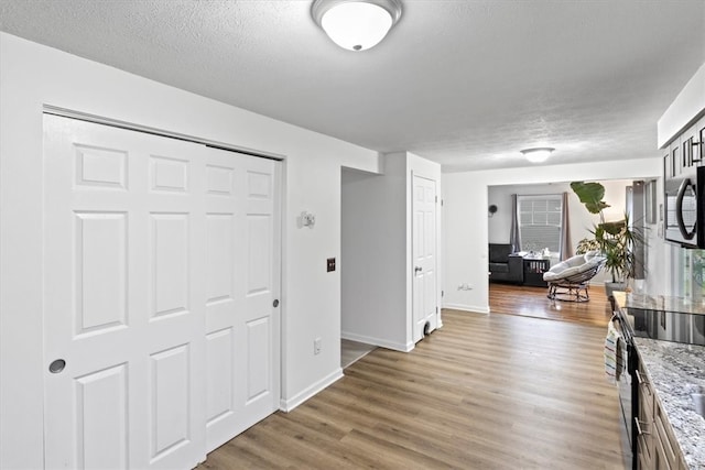 hall with wood-type flooring and a textured ceiling