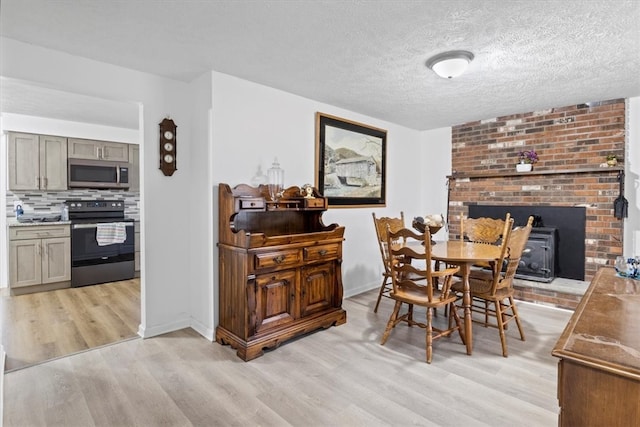 dining area with a textured ceiling, light wood-type flooring, and a wood stove