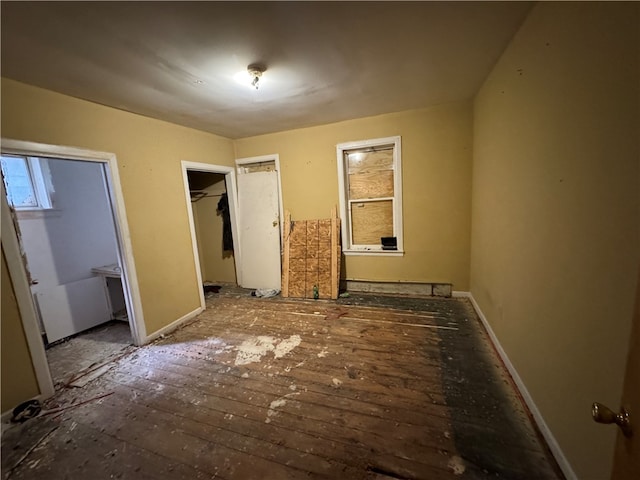 unfurnished bedroom featuring hardwood / wood-style floors, a spacious closet, and a closet