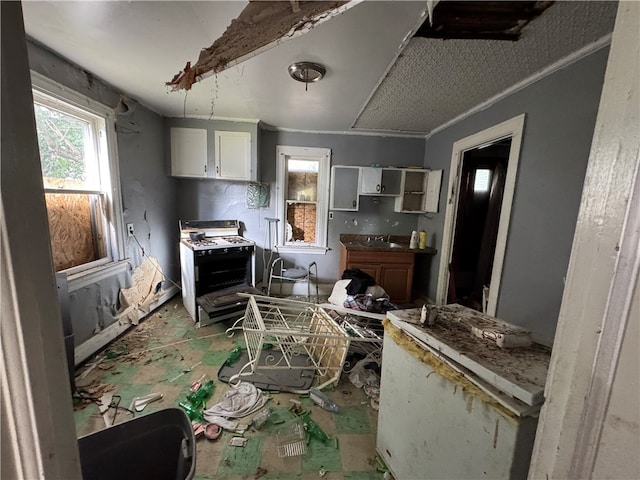 kitchen featuring white cabinets, sink, white range with gas stovetop, and ornamental molding