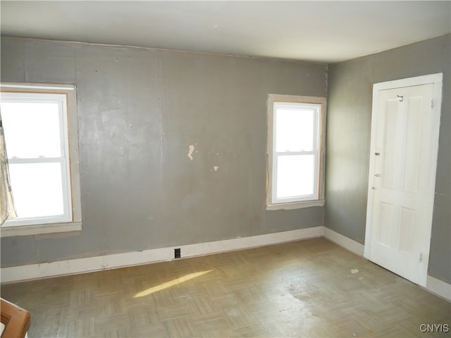 unfurnished room with plenty of natural light and parquet floors