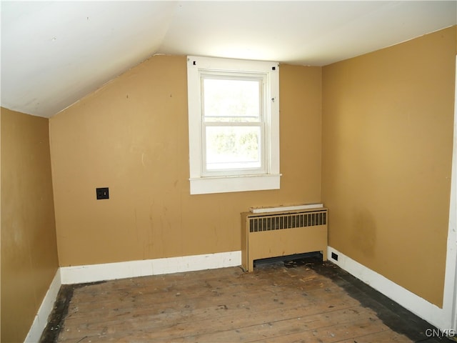 additional living space featuring dark hardwood / wood-style floors, radiator heating unit, and vaulted ceiling