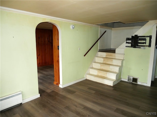 stairs featuring wood-type flooring, baseboard heating, and crown molding